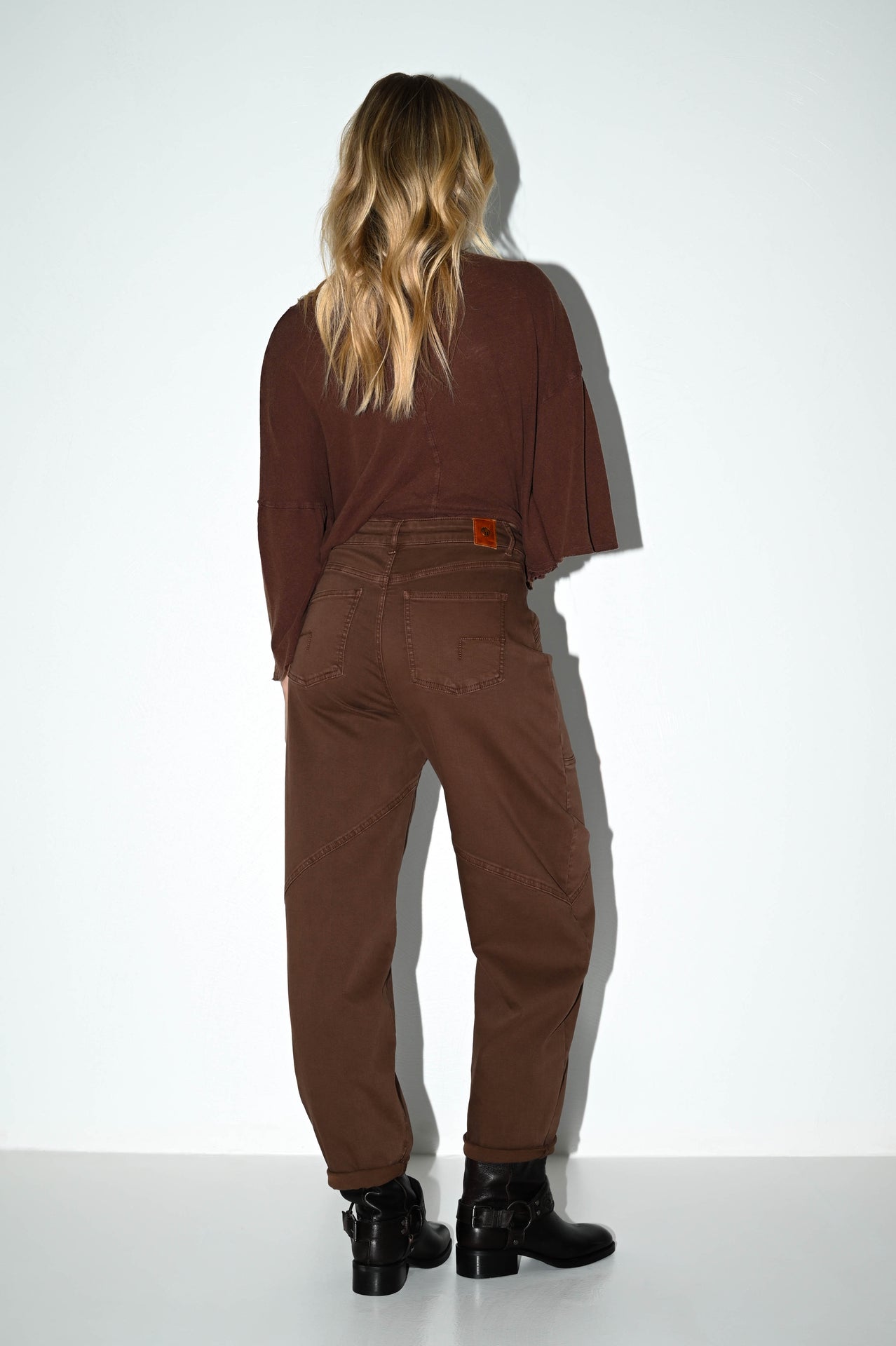 dame in de bruine barrel fit damesjeans bella die ze van de achterkant showt
