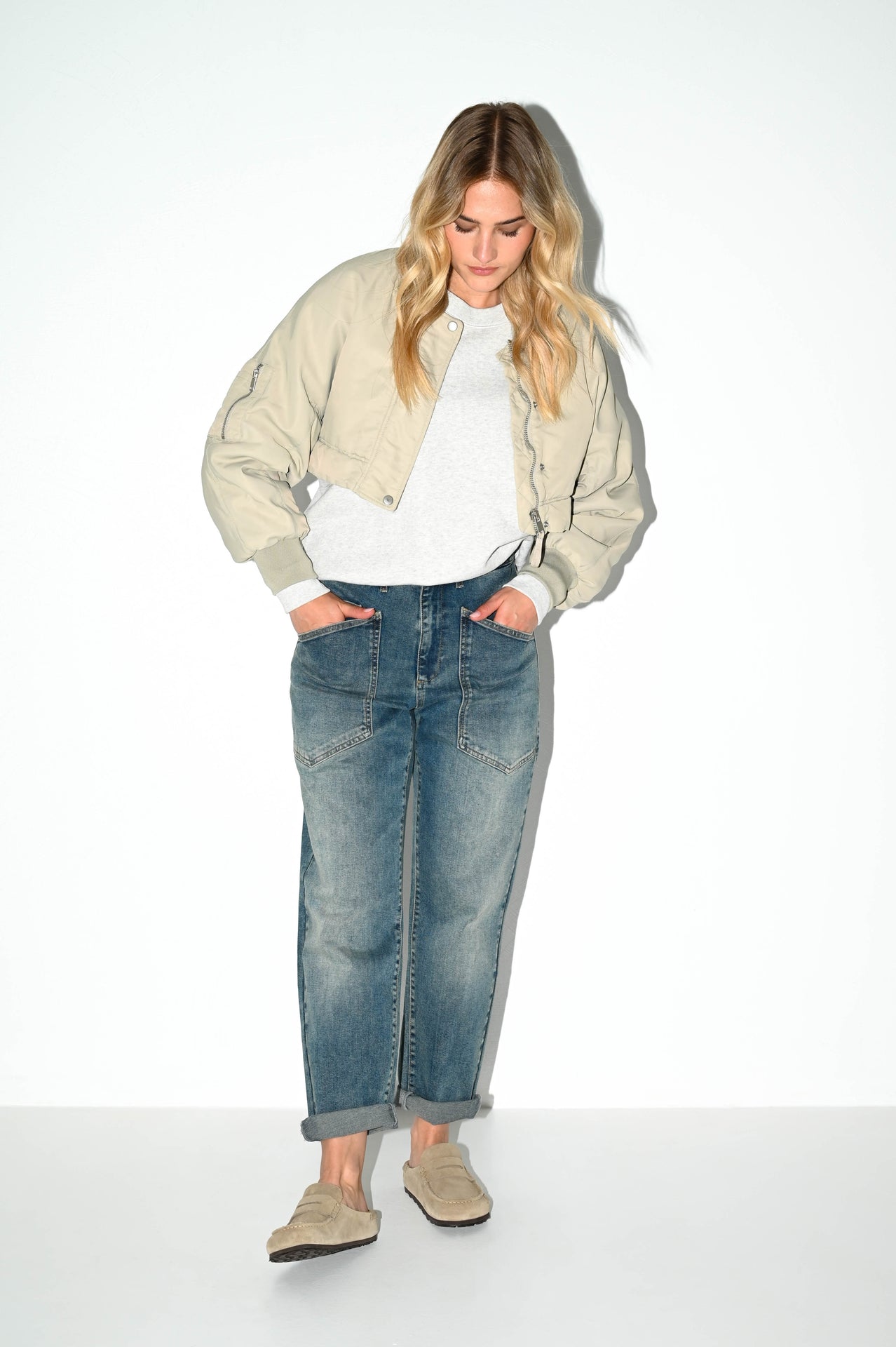 model draagt de jaclin grijsblauwe carrot fit jeans van dnm pure gecombineerd met witte top en off white jasje